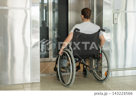 A Caucasian woman in a wheelchair uses an elevator. A Caucasian woman in a wheelchair uses an elevator. 143228566