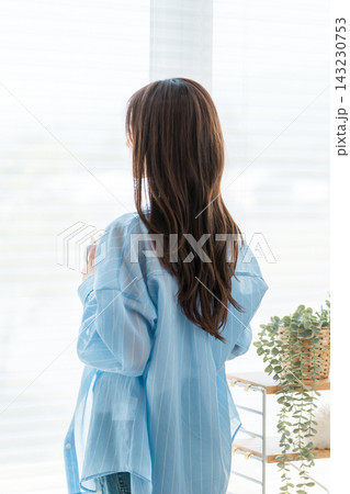 窓辺でホットドリンク,お茶,コーヒーを飲む若いアジア人女性の後ろ姿 窓辺でホットドリンク,お茶,コーヒーを飲む若いアジア人女性の後ろ姿 143230753
