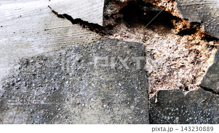 A severely damaged concrete wall with a large hole and exposed layers of plaster. A severely damaged concrete wall with a large hole and exposed layers of plaster. 143230889