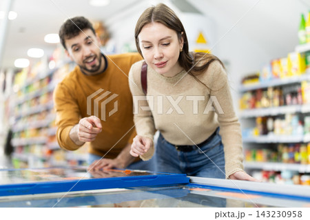 Young couple choosing frozen food in grocery store Young couple choosing frozen food in grocery store 143230958