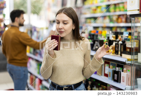 Woman customer sniffs perfume, choose spring fragrance perfume. Woman customer sniffs perfume, choose spring fragrance perfume. 143230983
