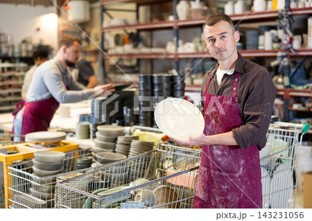 Enthusiastic ceramicist demonstrating handcrafted plates in ceramic studio Enthusiastic ceramicist demonstrating handcrafted plates in ceramic studio 143231056
