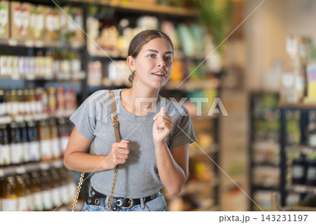 Young female shopper browsing grocery shelves at supermarket Young female shopper browsing grocery shelves at supermarket 143231197
