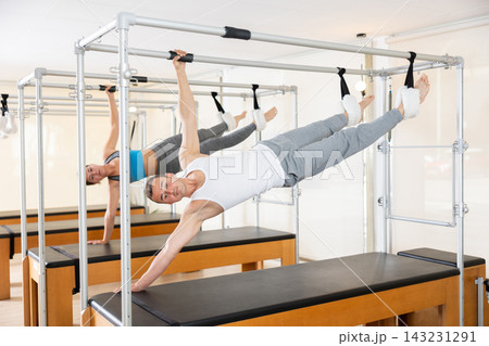 Man performing side hanging exercise on Pilates Cadillac 143231291