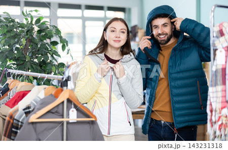 Couple trying on jackets in a clothing store Couple trying on jackets in a clothing store 143231318
