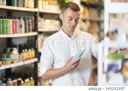 Interested male shopper choosing organic care products in eco store Interested male shopper choosing organic care products in eco store 143231397