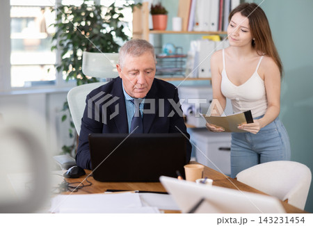 Female secretary brings folder with documents for company director to sign 143231454