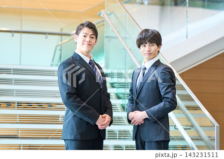 階段を背景に並んで立つ信頼感ある若いビジネスマン2人のポートレート 階段を背景に並んで立つ信頼感ある若いビジネスマン2人のポートレート 143231511