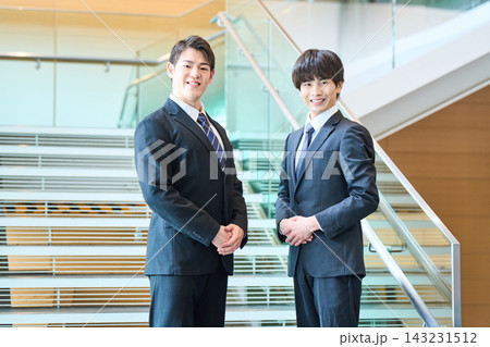 階段を背景に並んで立つ信頼感ある若いビジネスマン2人のポートレート 143231512