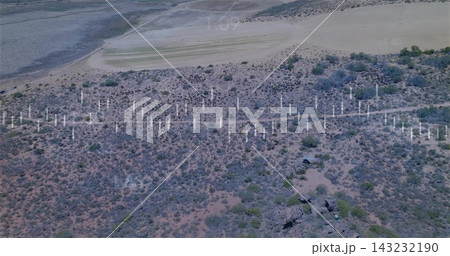 Showing midground band of white posts stretching across arid shrubland with rock outcrops 143232190