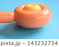 pastel orange comb on blue background, hair brush for pet 143232734