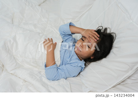 sick preschoool child girl touching her forehead with fever headache in bed sick preschoool child girl touching her forehead with fever headache in bed 143234004