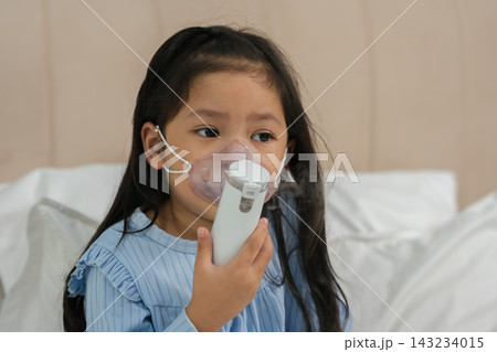 sick preschool child girl using respiratory nebulizer mask in bed 143234015