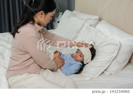 mother applying cold compress on sick daughter's forehead in bed mother applying cold compress on sick daughter's forehead in bed 143234060