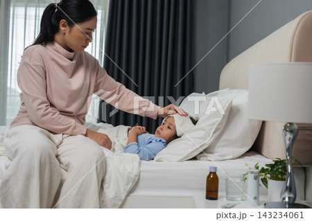 mother applying cold compress on sick daughter's forehead in bed 143234061