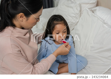 mother feeding liquid medicine to sick preschool child girl with a spoon mother feeding liquid medicine to sick preschool child girl with a spoon 143234064