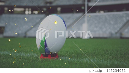 Focusing close rugby ball showing dew on red kicking tee at stadium pitch, gold sparkles Focusing close rugby ball showing dew on red kicking tee at stadium pitch, gold sparkles 143234951