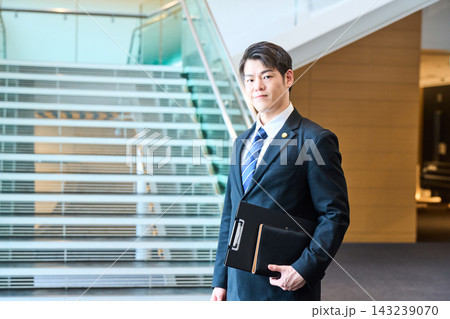 オフィスビルの階段前で自信に満ちた表情を浮かべる若い士業の日本人男性 143239070
