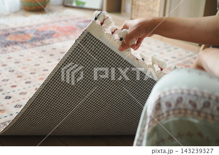 Person rolls rug on wooden floor in living room during daytime Person rolls rug on wooden floor in living room during daytime 143239327
