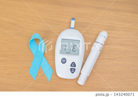 digital blood glucose meter with lancet pen and Blue Ribbon on table. high blood sugar level, November World Diabetes Day, Awareness month, Glycemia,, Hyperglycemia and insulin testing and checking digital blood glucose meter with lancet pen and Blue Ribbon on table. high blood sugar level, November World Diabetes Day, Awareness month, Glycemia,, Hyperglycemia and insulin testing and checking 143240071