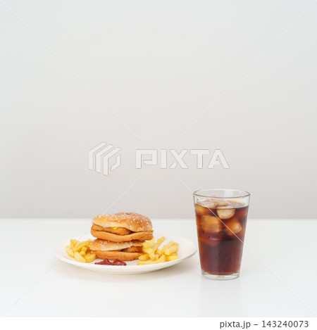 juicy beef burger with melted cheddar cheese, potato chips and carbonated Soft drinks on table. Unhealthy, High calorie, Fast food craving, Obesity, diet, weight loss, junk food and lifestyle juicy beef burger with melted cheddar cheese, potato chips and carbonated Soft drinks on table. Unhealthy, High calorie, Fast food craving, Obesity, diet, weight loss, junk food and lifestyle 143240073