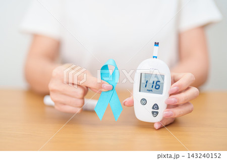 Hand show Blue Ribbon and digital blood glucose meter with lancet pen. high blood sugar level, November World Diabetes Day, Awareness month, Glycemia,, Hyperglycemia and insulin testing and checking Hand show Blue Ribbon and digital blood glucose meter with lancet pen. high blood sugar level, November World Diabetes Day, Awareness month, Glycemia,, Hyperglycemia and insulin testing and checking 143240152