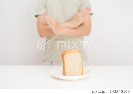Unhappy woman showing Rejecting gesture and refusing to eat bread. concept of gluten intolerance, gluten sensitivity, carb loading concerns, or a disliking for unhealthy dietary habits Unhappy woman showing Rejecting gesture and refusing to eat bread. concept of gluten intolerance, gluten sensitivity, carb loading concerns, or a disliking for unhealthy dietary habits 143240169