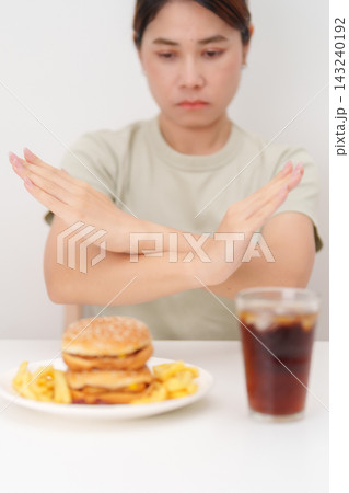 Unhappy woman showing Rejecting and refusing with Juicy beef burger, potato chips and carbonated Soft drinks. Unhealthy, High calorie, Fast food craving, Obesity, diet, weight loss and junk food 143240192