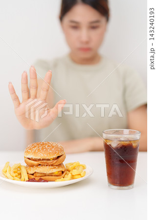 Unhappy woman showing Rejecting and refusing with Juicy beef burger, potato chips and carbonated Soft drinks. Unhealthy, High calorie, Fast food craving, Obesity, diet, weight loss and junk food Unhappy woman showing Rejecting and refusing with Juicy beef burger, potato chips and carbonated Soft drinks. Unhealthy, High calorie, Fast food craving, Obesity, diet, weight loss and junk food 143240193