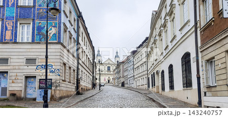 Historic cobblestone street in Warsaw leading towards a church with twin towers - Warsaw, Poland - January 26, 2023 143240757