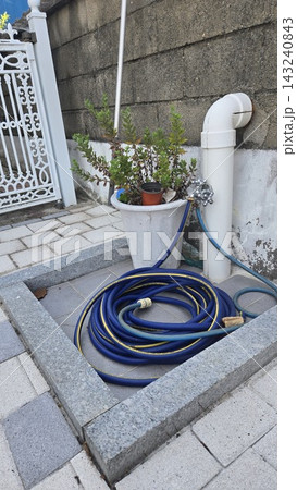 Blue garden hose reel next to flower pot on backyard patio 143240843