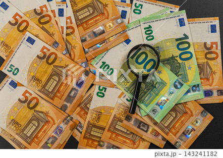 Magnifying glass placed on euro banknotes for financial inspection 143241182