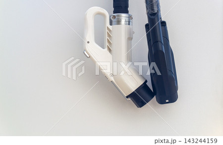 Modern electric vehicle charging station connectors hanging on clean white terminal wall with copy space Modern electric vehicle charging station connectors hanging on clean white terminal wall with copy space 143244159