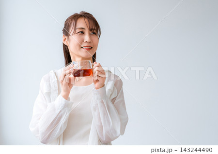 窓辺で温かい飲み物を楽しむ女性。家でくつろぐリラックスタイム 窓辺で温かい飲み物を楽しむ女性。家でくつろぐリラックスタイム 143244490