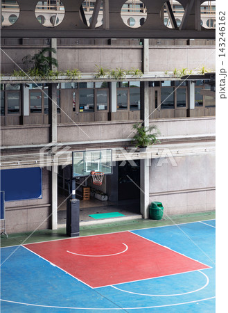 a uniquely sheltered basketball court framed by brutalist concrete architecture. Soft natural light filters down onto the crisp geometric lines of the court, where deep crimson and cool azure tones 143246162