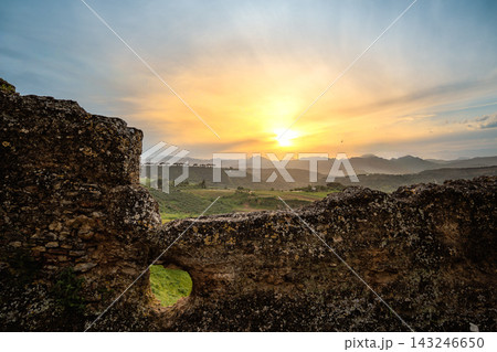 Sunset over the Andalusian countryside seen through an ancient stone wall Sunset over the Andalusian countryside seen through an ancient stone wall 143246650