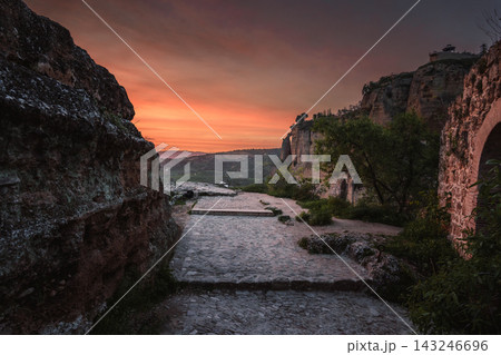 Cobblestone path between old walls leading to Ronda cliffs at sunset Cobblestone path between old walls leading to Ronda cliffs at sunset 143246696