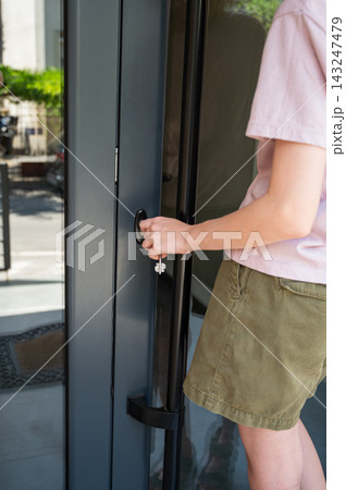 Person Opening Front Door of Modern Home in Daylight 143247479