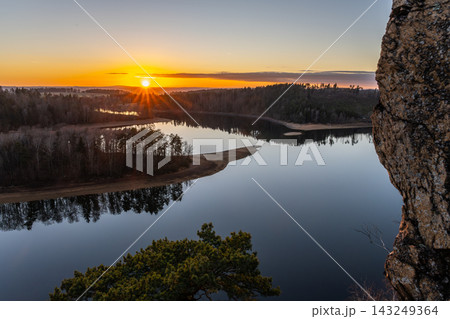 The sun sets over Sec Water reservoir, casting light on the water and trees. The sky shows warm colors and the surface reflects the scenery. A calm evening unfolds at this natural spot. 143249364