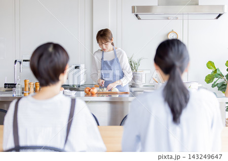 料理教室で玉ねぎの切り方を実演する日本人女性講師と生徒 料理教室で玉ねぎの切り方を実演する日本人女性講師と生徒 143249647