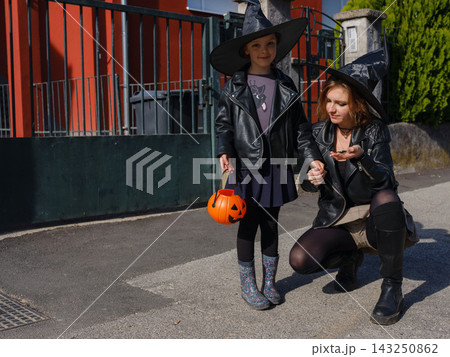 Mother and daughter enjoying Halloween trick or treat in neighborhood 143250862