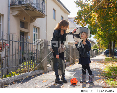 Mother and daughter enjoying Halloween trick or treat in neighborhood 143250863