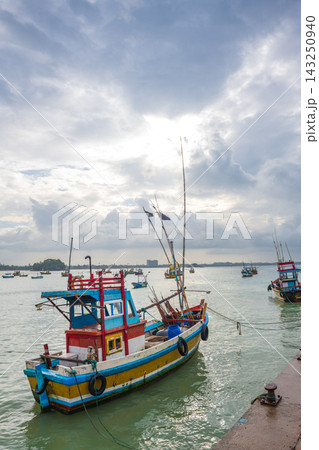 A colorful traditional fishing boat moored at Weligama harbor in Sri Lanka, surrounded by numerous fishing boats on calm coastal waters 143250940