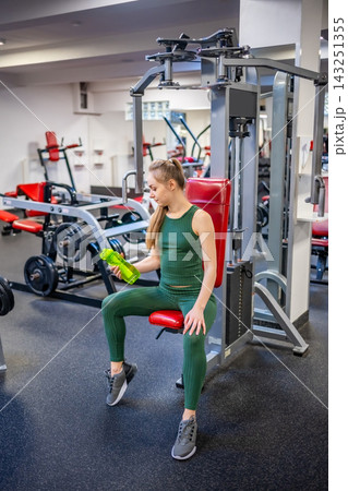 Young woman having break after sport training and drinking water from green glass bottle. Self care, life balance and healthy lifestyle concept. 143251355