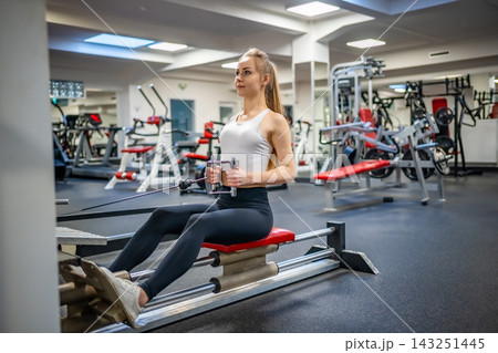 Young sport woman wearing sport wear doing exercise with fitness equipment at gym, she exercise for strong back and good healthy Young sport woman wearing sport wear doing exercise with fitness equipment at gym, she exercise for strong back and good healthy 143251445