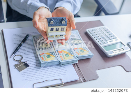 Realtor, home buyer signs a contract of loan approve with cash down payment on table and holding house model Realtor, home buyer signs a contract of loan approve with cash down payment on table and holding house model 143252078