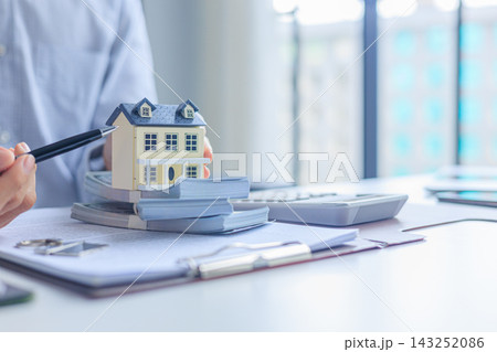 Real estate broker desk with house model, money, and calculator. Mortgage estimation and property purchasing concept. Real estate broker desk with house model, money, and calculator. Mortgage estimation and property purchasing concept. 143252086