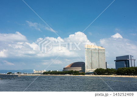 青空と白い雲が広がる海辺に、福岡ドームや高層ホテルが佇む百道浜のウォーターフロント景観 143252409