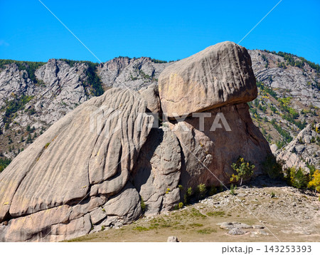 conic Turtle Rock Formation, standing 24 meters tall against rocky mountain peaks under a clear blue sky in Gorkhi-Terelj National Park, Mongolia 143253393