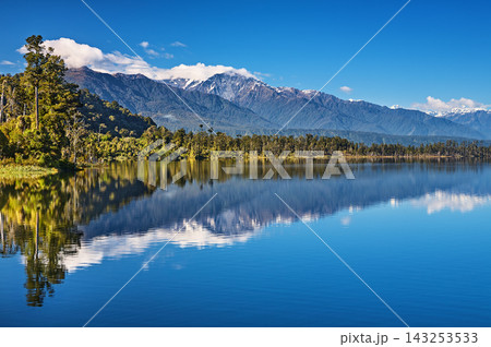 Beautiful lake Ianthe at the bottom of Southern Alps on The West Coast of South Island in New Zealand, mountains, forest, blue sky with reflection Beautiful lake Ianthe at the bottom of Southern Alps on The West Coast of South Island in New Zealand, mountains, forest, blue sky with reflection 143253533